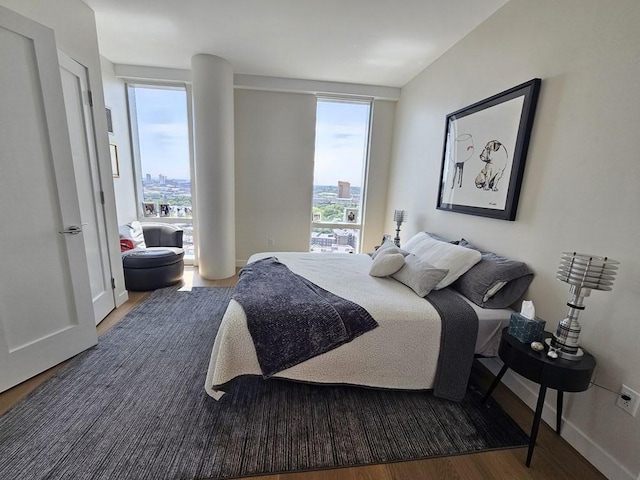 bedroom with floor to ceiling windows and dark hardwood / wood-style floors