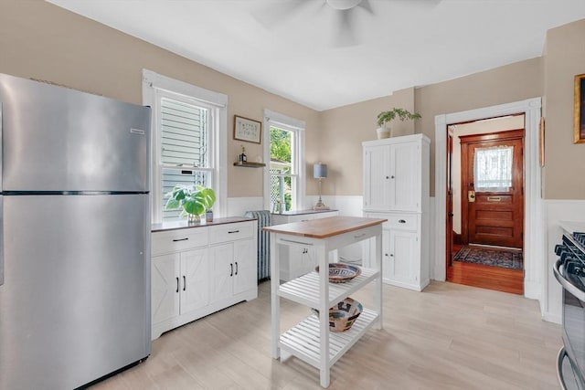 50 Oleander St, West Springfield, MA 01089 - kitchen with stainless steel appliances, white cabinets, ceiling fan, light wood-style flooring, and wainscoting