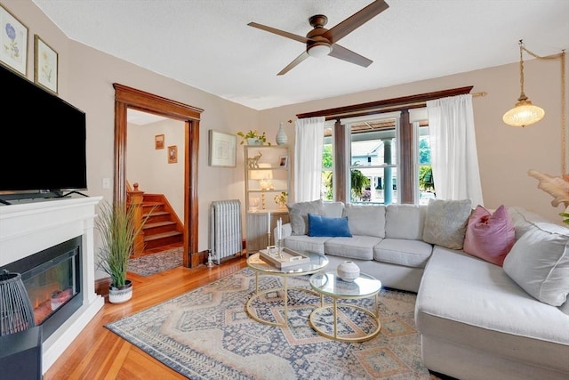 50 Oleander St, West Springfield, MA 01089 - living area with radiator heating unit, ceiling fan, wood finished floors, stairs, and a glass covered fireplace