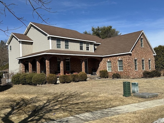 view of front of home with brick siding, a porch, and roof with shingles