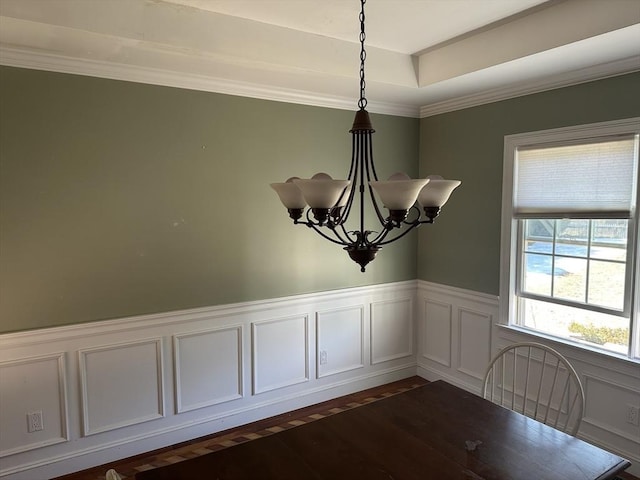 unfurnished dining area with a wainscoted wall, an inviting chandelier, dark wood-style floors, and crown molding