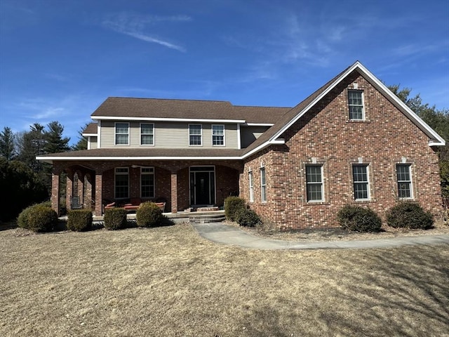 view of front facade with brick siding and covered porch