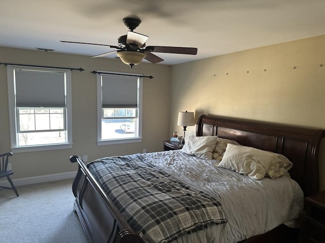 carpeted bedroom with multiple windows, a ceiling fan, and baseboards