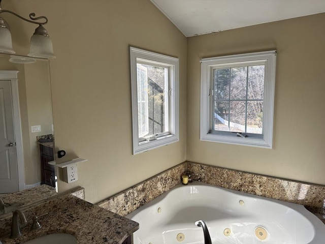 full bath featuring vaulted ceiling, vanity, and a whirlpool tub