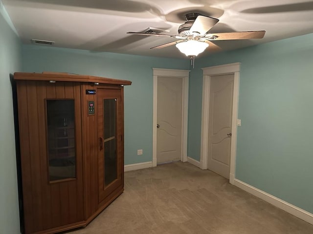 empty room with ceiling fan, baseboards, visible vents, and light carpet