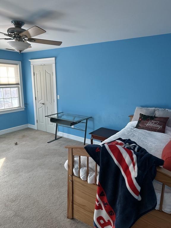 carpeted bedroom with a ceiling fan and baseboards