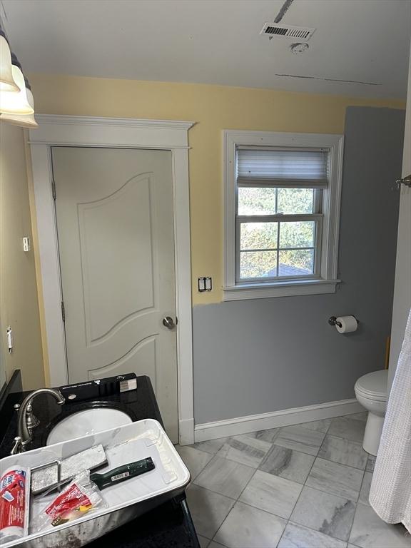 bathroom featuring baseboards, visible vents, a sink, toilet, and marble finish floor