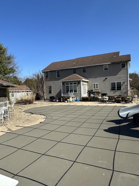 rear view of property with a covered pool and a patio area