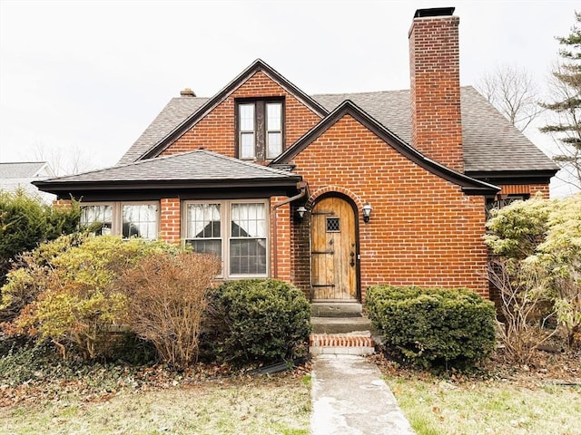 view of front of property with a chimney, a shingled roof, and brick siding