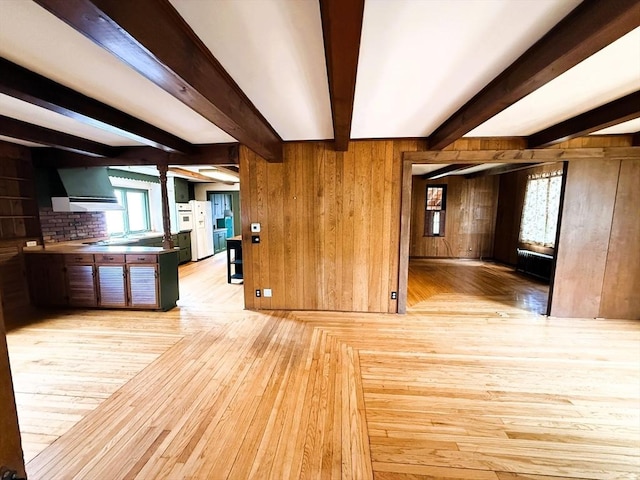 unfurnished living room with hardwood / wood-style floors, wood walls, and beam ceiling