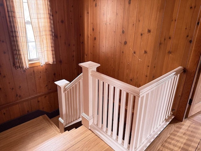 stairway featuring wooden walls