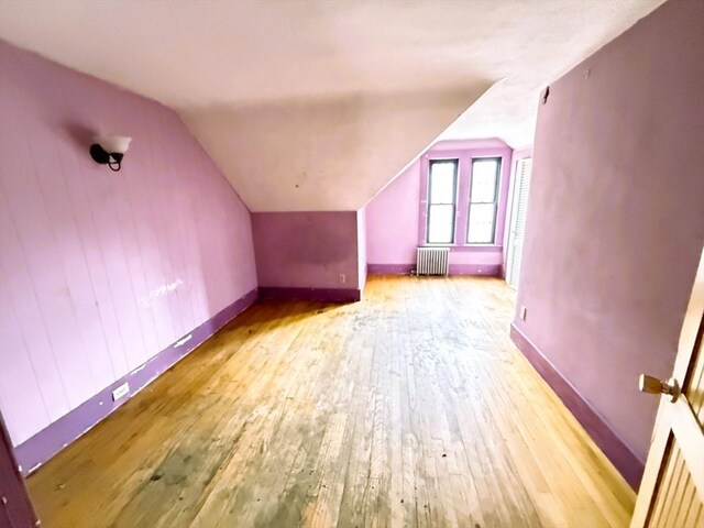 bonus room featuring radiator, baseboards, lofted ceiling, and hardwood / wood-style flooring
