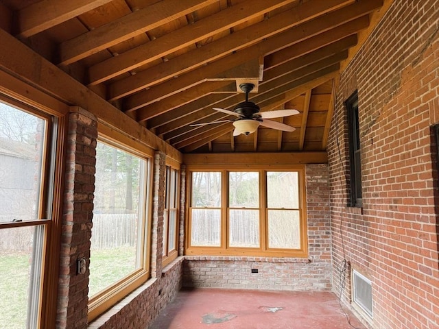 unfurnished sunroom with visible vents, plenty of natural light, vaulted ceiling, and brick wall
