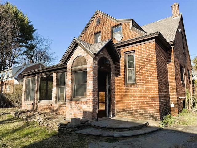view of front of home featuring brick siding and a chimney