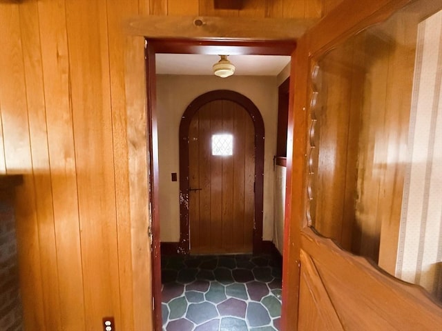 doorway to outside featuring wood walls and arched walkways