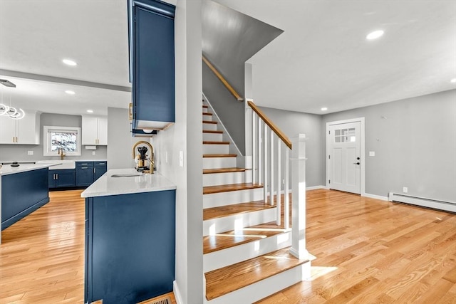 stairs featuring hardwood / wood-style flooring, a baseboard heating unit, and sink