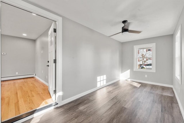 empty room featuring hardwood / wood-style floors, ceiling fan, and a baseboard heating unit