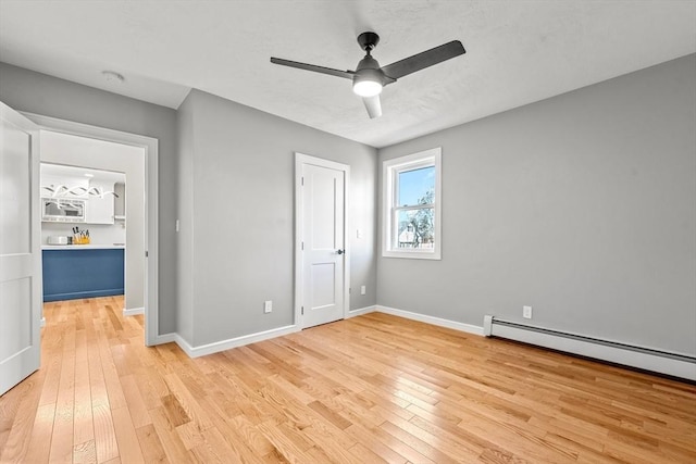 unfurnished bedroom with baseboard heating, ceiling fan, and light hardwood / wood-style floors