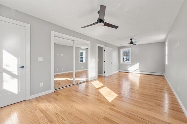 interior space featuring ceiling fan, light wood-type flooring, and a baseboard heating unit