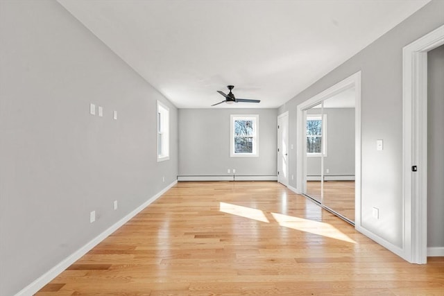 empty room featuring baseboard heating, ceiling fan, and plenty of natural light