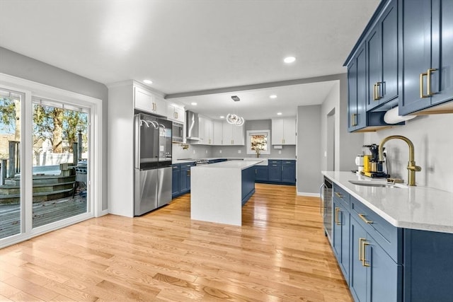 kitchen featuring blue cabinets, sink, a center island, stainless steel refrigerator, and hanging light fixtures