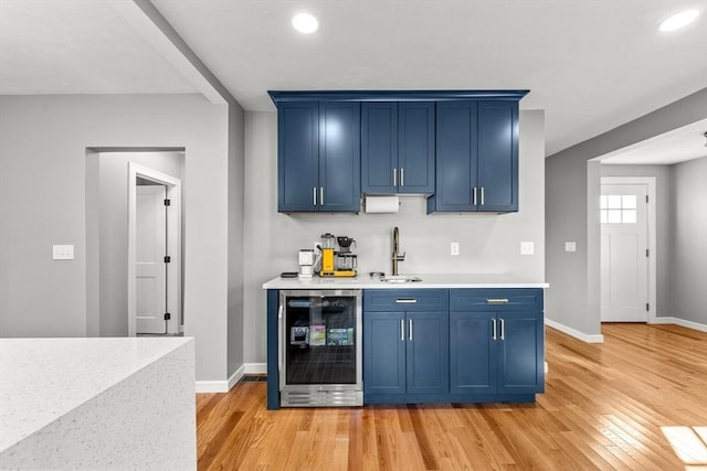 bar featuring blue cabinets, beverage cooler, and sink