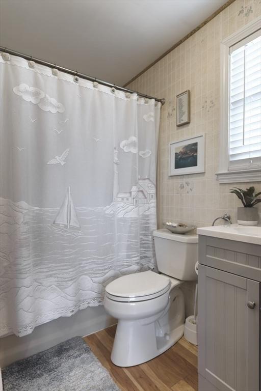 18 River St, Seabrook, NH 03874 - bathroom with toilet, wood finished floors, vanity, shower / bathtub combination with curtain, and tile walls
