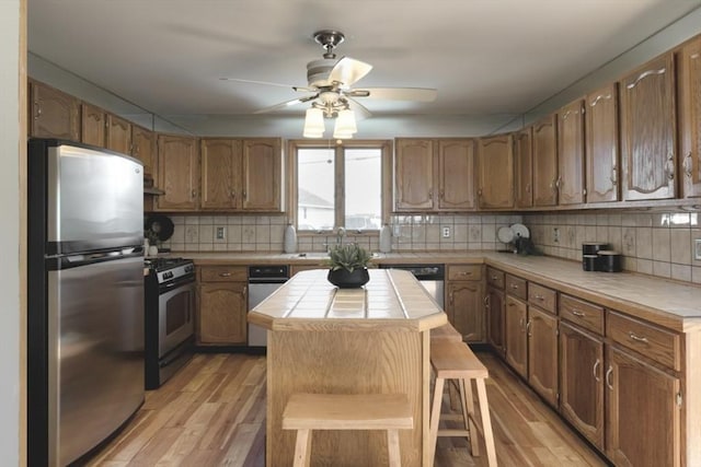 18 River St, Seabrook, NH 03874 - kitchen with stainless steel appliances, tile countertops, a ceiling fan, a center island, and backsplash