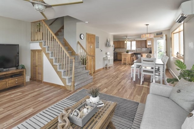 18 River St, Seabrook, NH 03874 - living room with baseboards, a wall mounted air conditioner, stairway, and light wood-style floors
