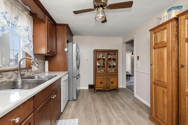 kitchen featuring sink, stainless steel fridge, dishwasher, tasteful backsplash, and light wood-type flooring