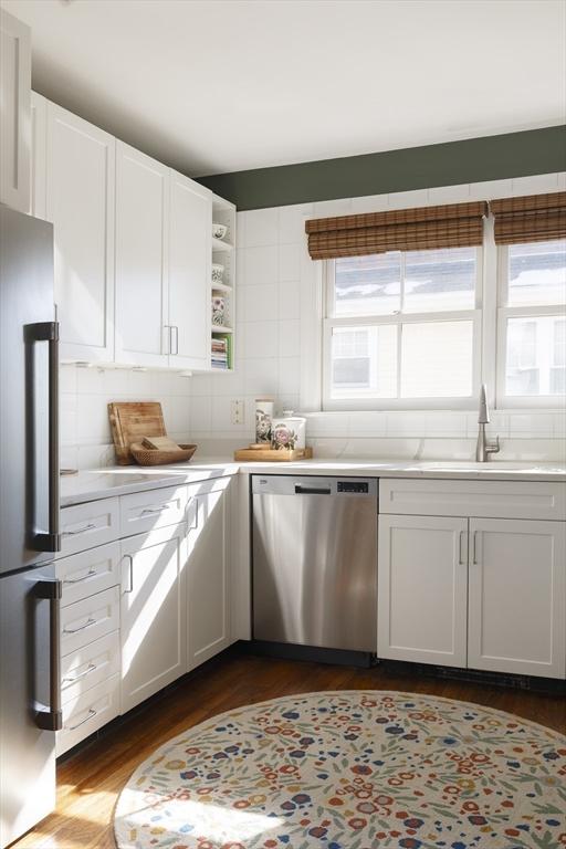 kitchen featuring white cabinetry, stainless steel appliances, dark hardwood / wood-style flooring, sink, and backsplash