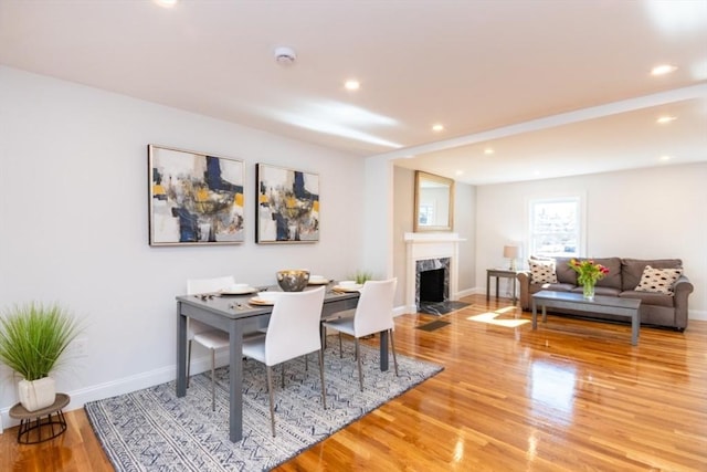 dining room with a premium fireplace, recessed lighting, wood finished floors, and baseboards