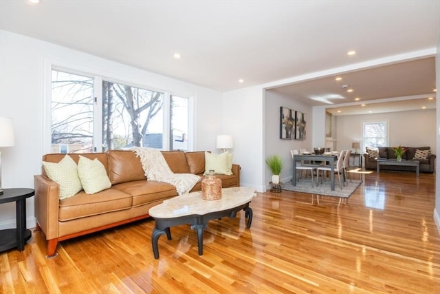 living area with baseboards, light wood-style floors, recessed lighting, and a healthy amount of sunlight