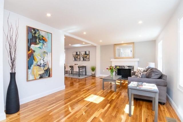 living room featuring recessed lighting, visible vents, baseboards, light wood-style flooring, and a high end fireplace