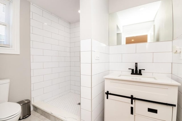 full bath with toilet, tile walls, tiled shower, and vanity