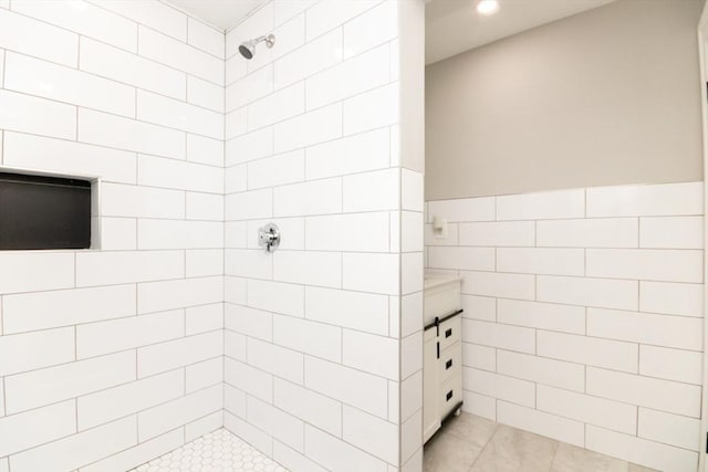 full bath featuring wainscoting, tile patterned flooring, a tile shower, and tile walls