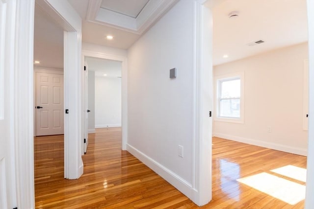 hallway featuring attic access, baseboards, visible vents, and light wood finished floors