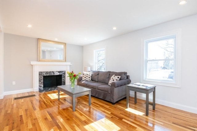 living area with light wood-style floors, recessed lighting, a fireplace, and baseboards