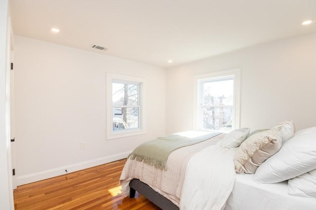 bedroom with light wood-type flooring, multiple windows, baseboards, and recessed lighting