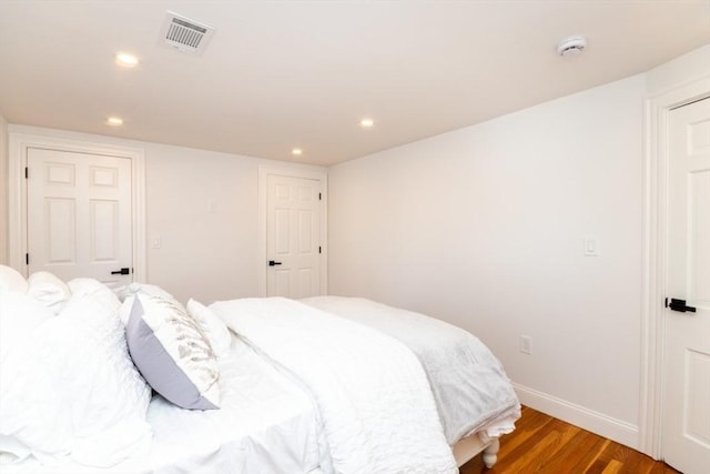 bedroom with baseboards, visible vents, wood finished floors, and recessed lighting