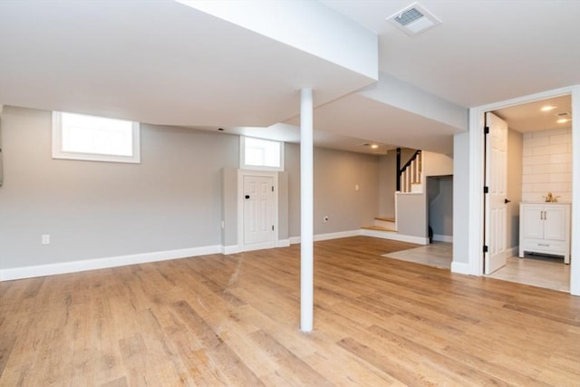 basement featuring light wood-style floors, baseboards, stairs, and visible vents