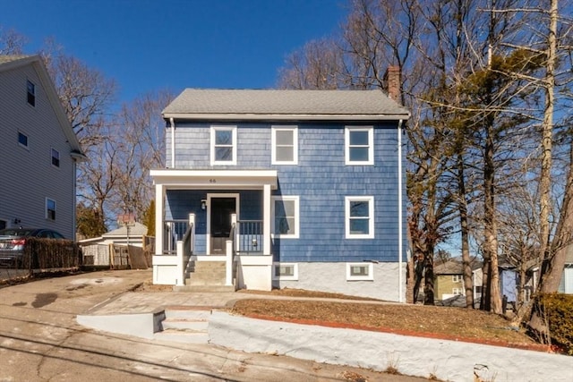 traditional home featuring covered porch, driveway, and a chimney