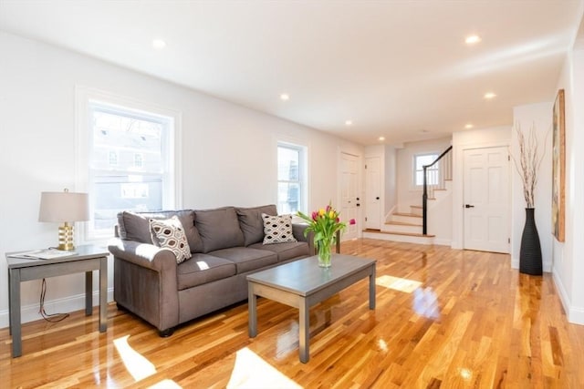 living room with recessed lighting, light wood-style flooring, baseboards, and stairs