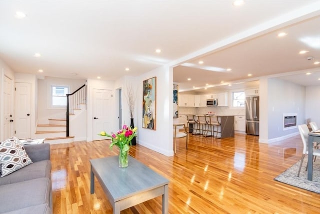 living room with stairs, light wood-style floors, plenty of natural light, and heating unit