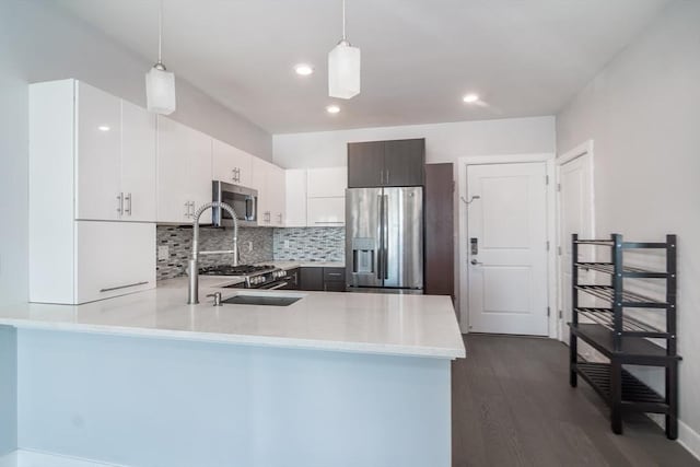 kitchen with white cabinets, stainless steel appliances, dark brown cabinetry, and hanging light fixtures