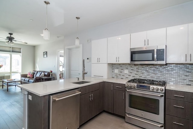 kitchen featuring white cabinets, appliances with stainless steel finishes, decorative light fixtures, decorative backsplash, and dark brown cabinets