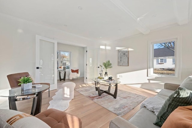 living room featuring ornamental molding, light wood-type flooring, beam ceiling, and baseboards