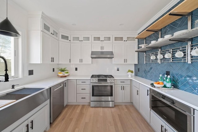 kitchen featuring light wood finished floors, open shelves, stainless steel appliances, a sink, and under cabinet range hood