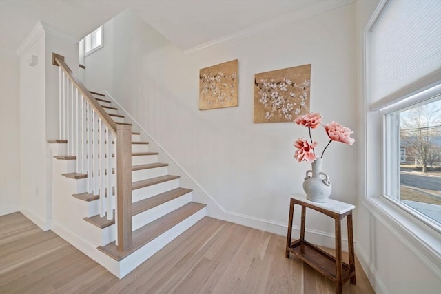 stairway with baseboards, wood finished floors, and crown molding