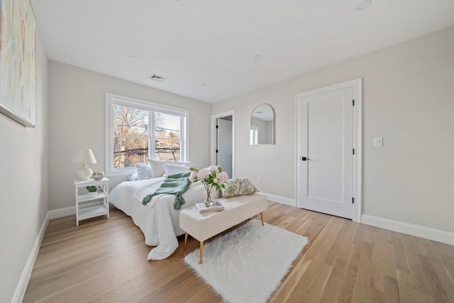 bedroom featuring light wood-style floors, visible vents, and baseboards